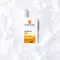 A bottle of La Roche-Posay Anthelios Invisible Fluid sunscreen with SPF 50+, featuring details about high protection and water resistance, displayed on a snow-like background.