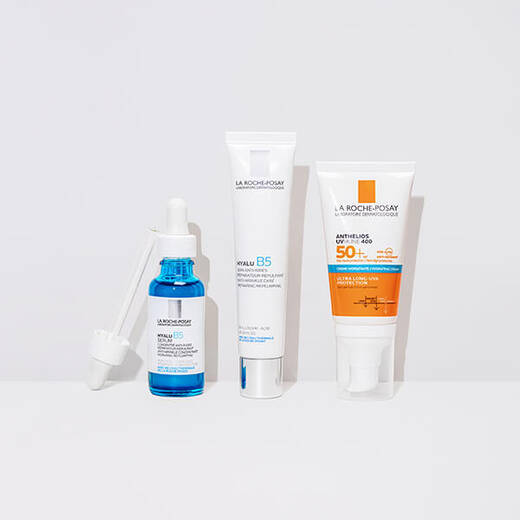 Hyalu B5 Serum, Hyalu B5 Cream and Anthelios UVMune 400 Hydrating Cream standing against a bright white background and on a reflective surface