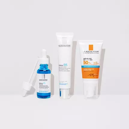 Three skincare products lined up against a white background: a blue serum in a dropper bottle, a white cream tube labeled "Hyaluronic Acid," and a sunscreen tube with a bright orange label indicating SPF 50+.
