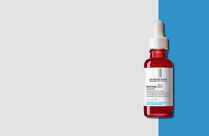 A clear dropper bottle with a red serum inside, labeled with skincare product branding on a split background of light gray and bright blue.