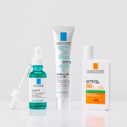 Three skincare products displayed on a neutral background: a blue serum with a dropper, a white tube of cream, and an orange bottle of sunscreen.