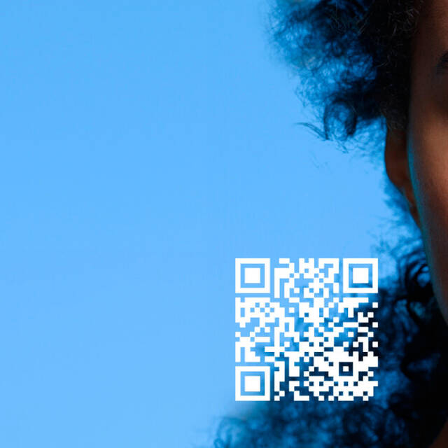 A close-up of a person's face with one side reflecting the digital display of a smartphone, featuring a QR code and a blue background.