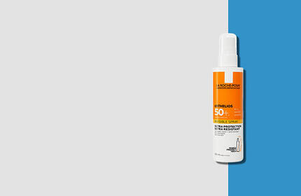 A bottle of sunscreen spray with SPF 50, featuring an orange and white design, set against a light grey and blue background.