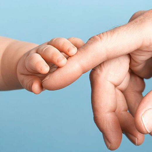 A close-up of a baby's hand reaching for an adult hand, symbolizing connection and tenderness.