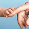 A close-up of a baby's hand reaching for an adult hand, symbolizing connection and tenderness.