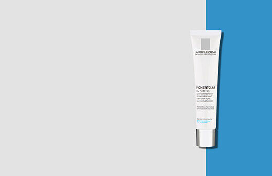 A white tube of skincare product with a silver cap, set against a minimalistic gray and blue background.