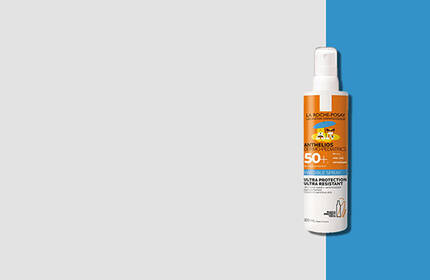 A bottle of sunscreen spray for pets with an orange label, placed against a split background of light gray and bright blue.