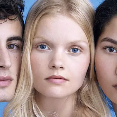 A close-up portrait of three individuals with various features, arranged side by side against a light blue background. They have neutral expressions and are looking directly at the camera, showcasing their diverse appearances.