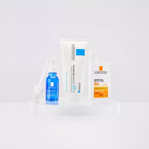 Niacinamide Serum, Toleriane Dermallergo Cream and Anthelio Pigment Correct standing against a bright white background and on a reflective surface