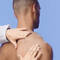 A close-up of a man's shoulder with a hand gently touching it, set against a light blue background.