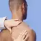 A close-up of a man's shoulder with a hand gently touching it, set against a light blue background.