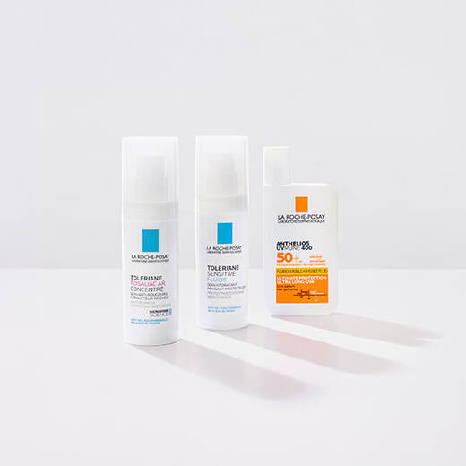 Niacinamide Serum, Toleriane Dermallergo Cream and Anthelio Pigment Correct standing against a bright white background and on a reflective surface