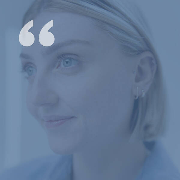 A close-up portrait of a young woman with short blonde hair, wearing earrings, and looking thoughtfully to the side against a soft blue background.