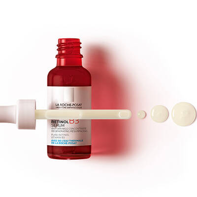 A red dropper bottle of La Roche-Posay Retinol B3 serum with a pipette and several drops of the serum displayed next to it.