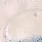 Abstract image of bubbles and liquid, featuring a curved line and a textured surface with varying shades of light.