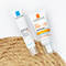 Two skincare products from La Roche-Posay are displayed: an Effaclar Duo SPF 30 and an Anthelios 50+ anti-imperfections cream. They are arranged on a textured surface, likely to emphasize their focus on skin protection and correction.