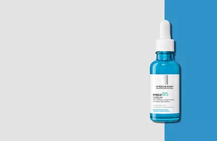 A bottle of bright blue serum with a dropper, set against a split background of gray and blue.