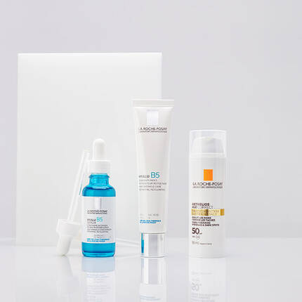 Three skincare products from La Roche-Posay displayed on a white background: a blue serum in a dropper bottle, a cream in a white tube, and a sunscreen in a white bottle with a pump.