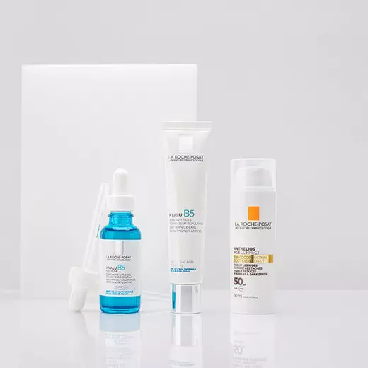 Hyalu B5 Serum, Hyalu B5 Cream and Anthelios Age Correct standing against a bright white background and on a reflective surface