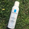 A bottle of La Roche-Posay thermal water spray lying on green grass.