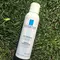 A bottle of La Roche-Posay thermal water spray lying on green grass.