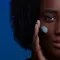 Woman applying sunscreen to her cheek with her fingers.
