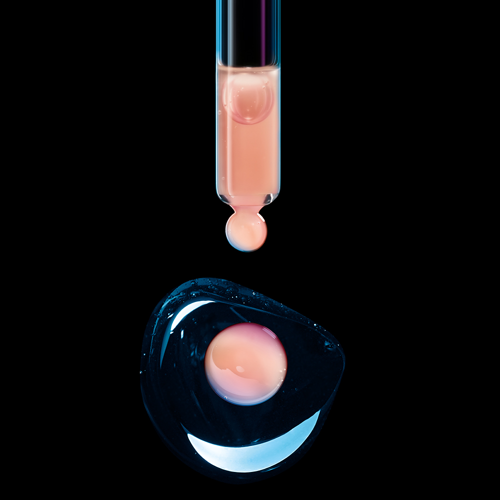 Striking close up of a pipette dispensing a peach coloured serum