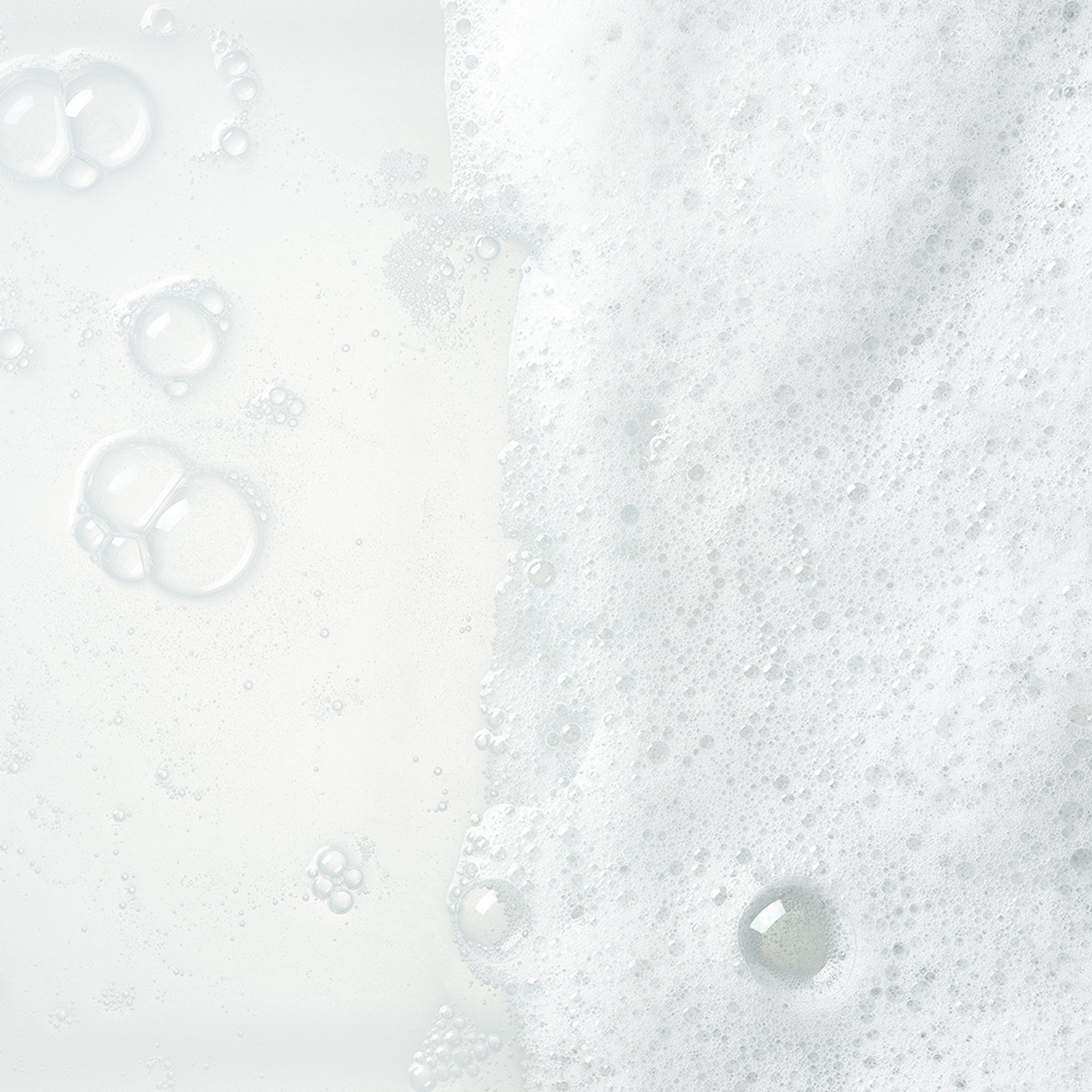 Close-up of white foam and bubbles on a light background, creating a soft and calming texture.