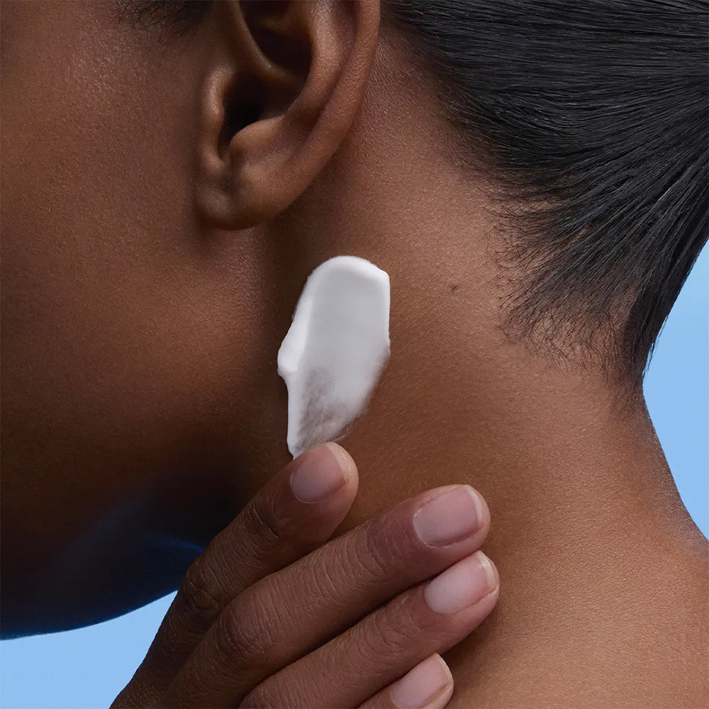 Woman applying a moisturising cream to her neck